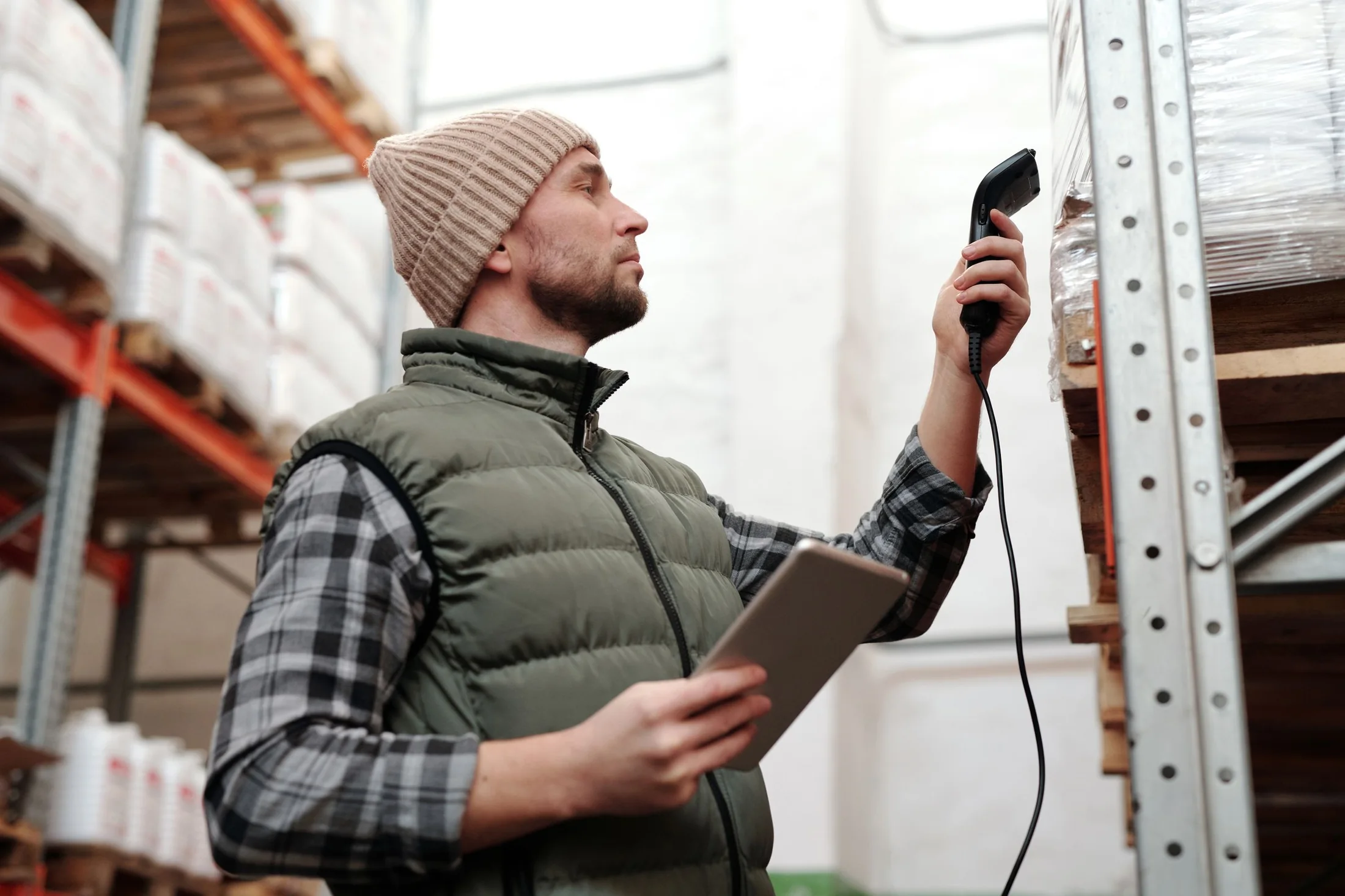 Warehouse worker using a handheld scanner beside pallet racking